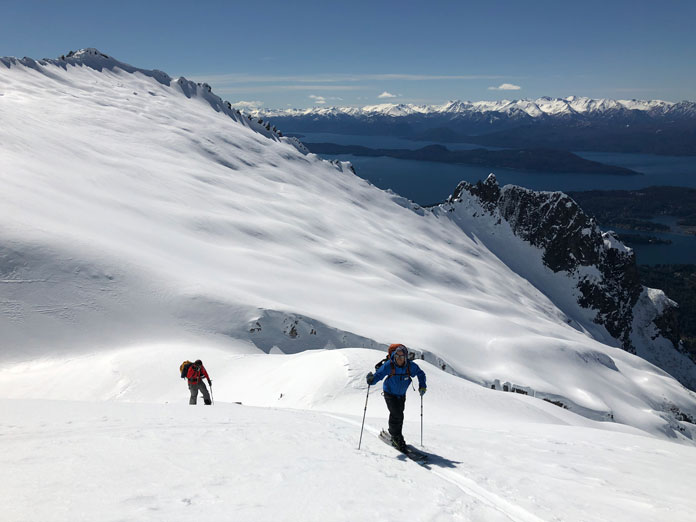 Skiers nearing summit of Cerro Lopez with spectacular views back over Lake Nahuel Huapi, Bariloche