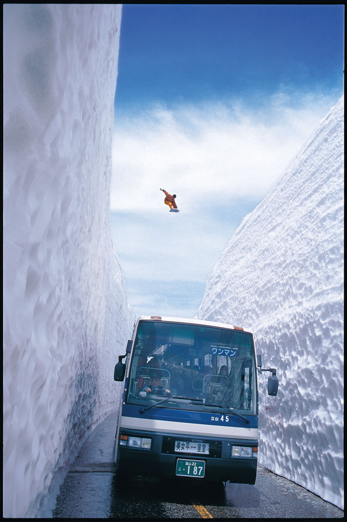 Snowboarder leaps over bus across the Tateyama Road Gap
